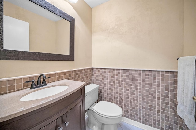 bathroom with vanity, toilet, and tile walls