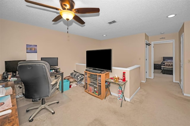 carpeted office featuring ceiling fan and a textured ceiling