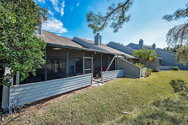 rear view of house with a yard and a sunroom