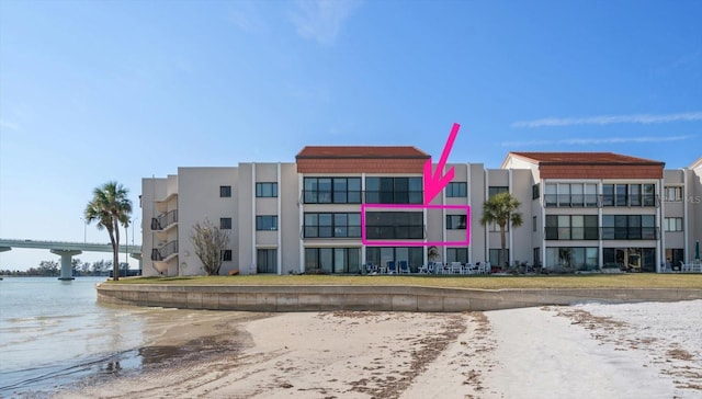 view of building exterior featuring a water view and a beach view