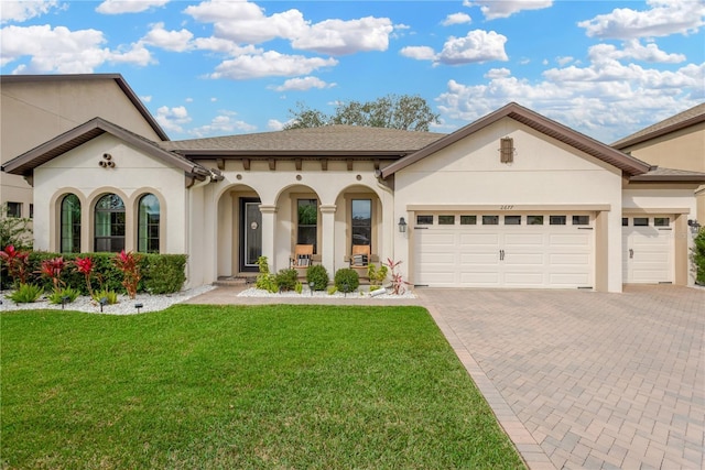 view of front of property with a garage, stucco siding, decorative driveway, and a front lawn