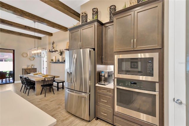 kitchen featuring dark brown cabinets, light countertops, hanging light fixtures, and stainless steel appliances