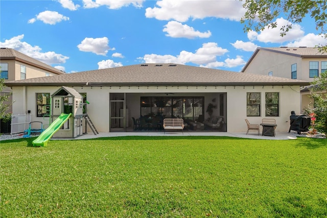 rear view of property with stucco siding, a yard, a playground, and a patio area