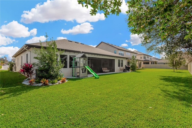 rear view of property with a sunroom, a lawn, stucco siding, and fence