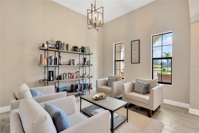 living area with baseboards, an inviting chandelier, and light wood-style floors