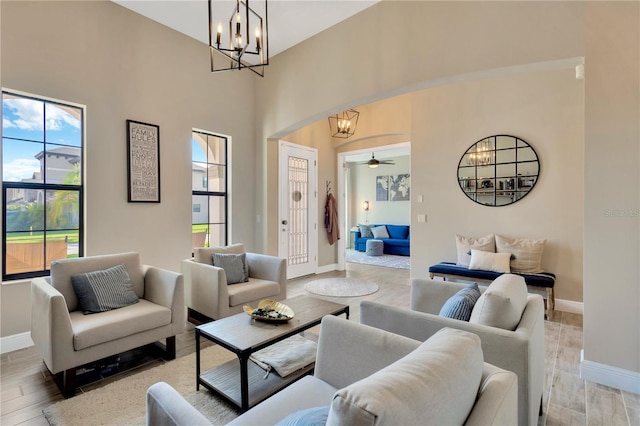 living room featuring arched walkways, baseboards, and light wood-style floors