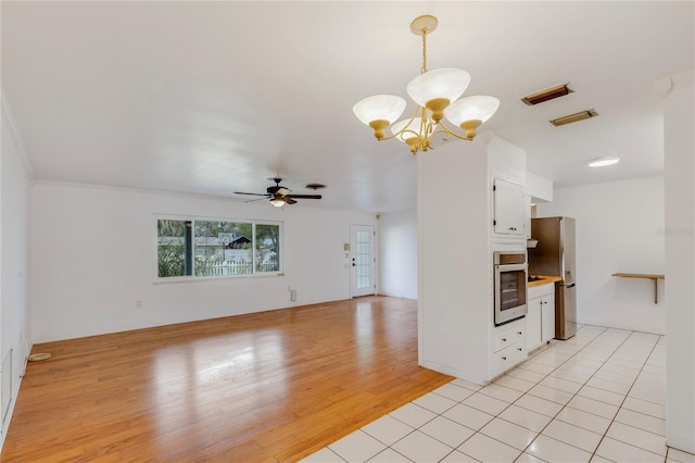 kitchen with white cabinets, open floor plan, light countertops, appliances with stainless steel finishes, and light wood finished floors