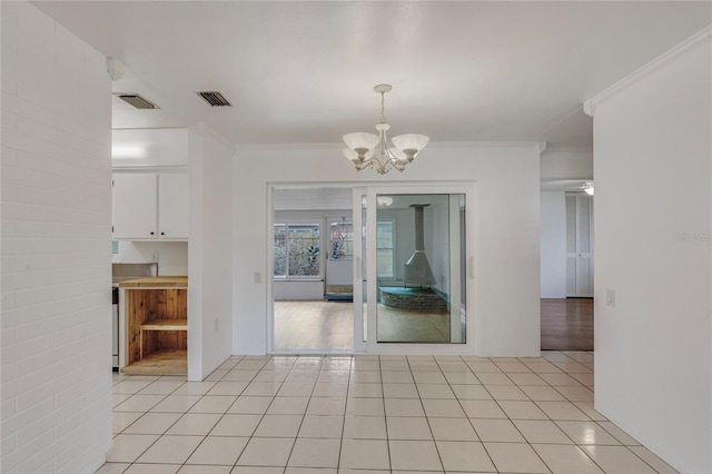 unfurnished dining area featuring light tile patterned floors, a chandelier, visible vents, and crown molding