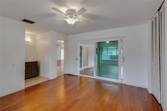 empty room with light wood finished floors, ceiling fan, visible vents, and baseboards