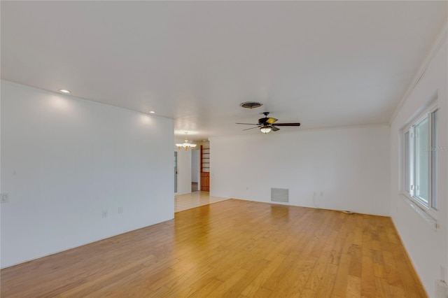 unfurnished room with light wood-style flooring, visible vents, and ornamental molding