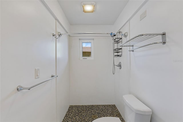 full bathroom featuring a tile shower and toilet