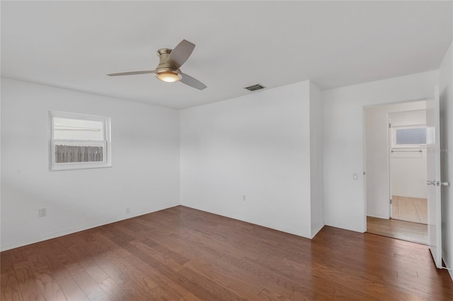 unfurnished room featuring ceiling fan, dark wood-style flooring, visible vents, and baseboards