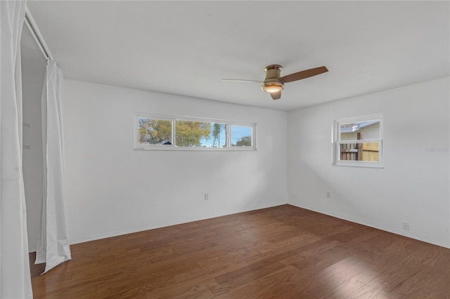 spare room featuring dark wood-style floors, a ceiling fan, and baseboards