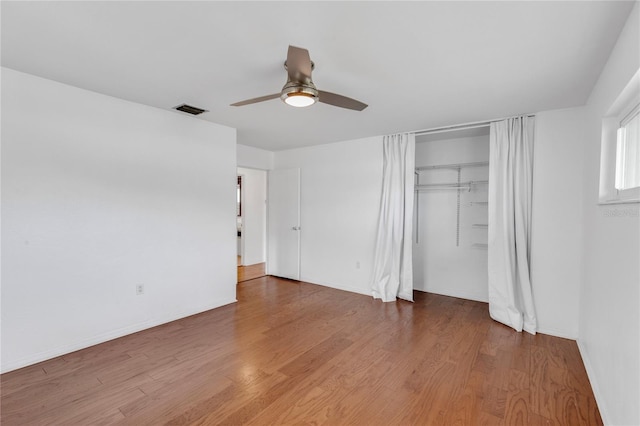 unfurnished bedroom with ceiling fan, a closet, visible vents, and wood finished floors