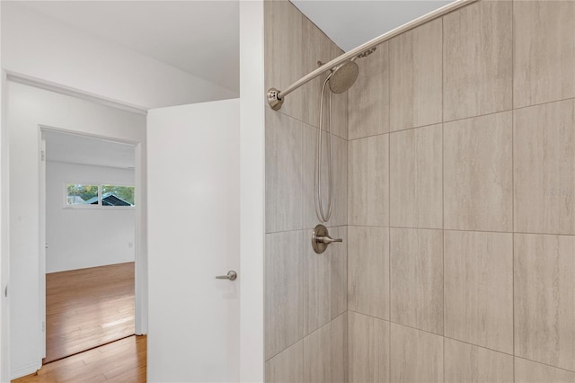 bathroom with tiled shower and wood finished floors