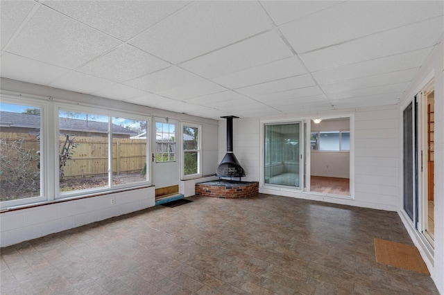 unfurnished sunroom with a drop ceiling and a wood stove