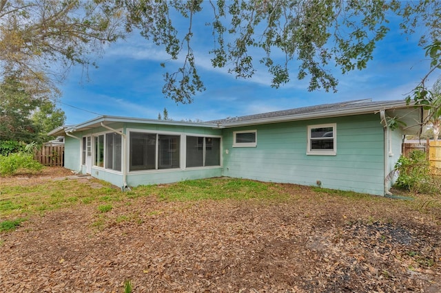 rear view of house with a sunroom and fence