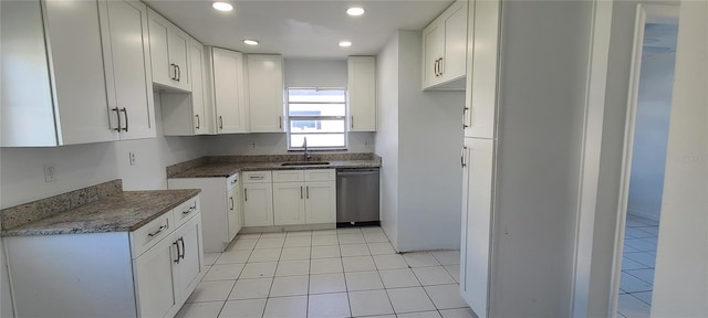 kitchen featuring stainless steel dishwasher, light tile patterned floors, sink, and white cabinets