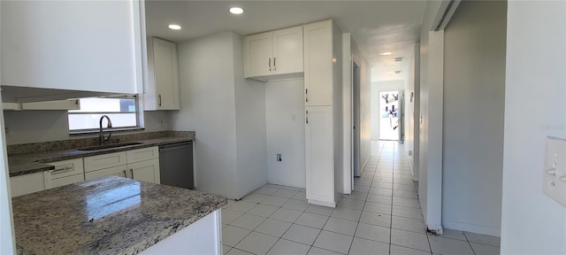 kitchen with sink, white cabinetry, dark stone countertops, black dishwasher, and light tile patterned flooring