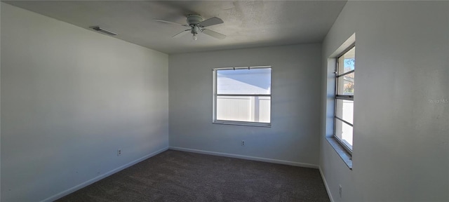 empty room with ceiling fan and dark colored carpet