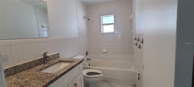 full bathroom featuring tiled shower / bath, tile walls, vanity, toilet, and tile patterned floors