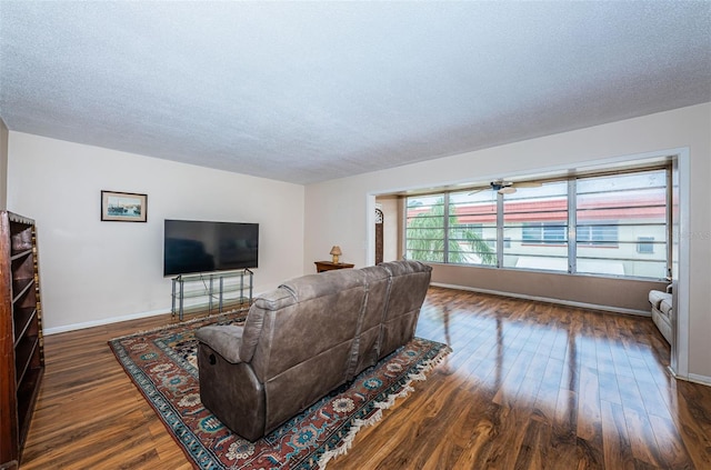 living room featuring a textured ceiling, baseboards, and dark wood-type flooring