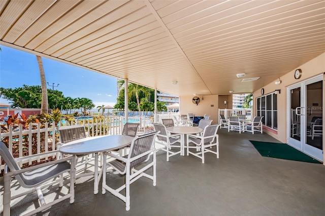 view of patio / terrace with a community pool, fence, and outdoor dining area