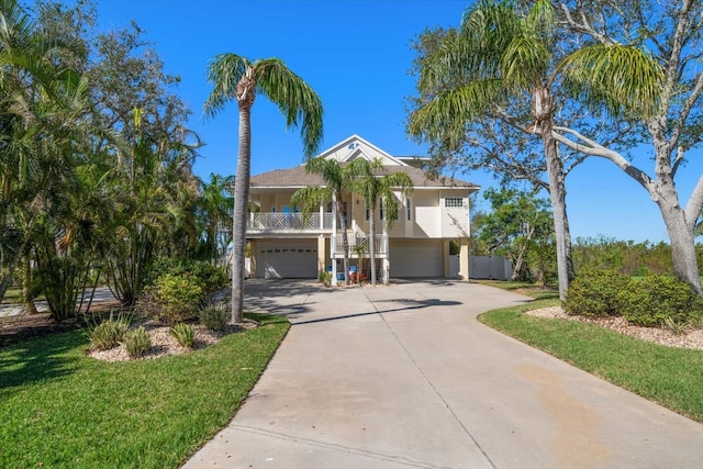 beach home with driveway, a garage, stairway, a porch, and a front yard