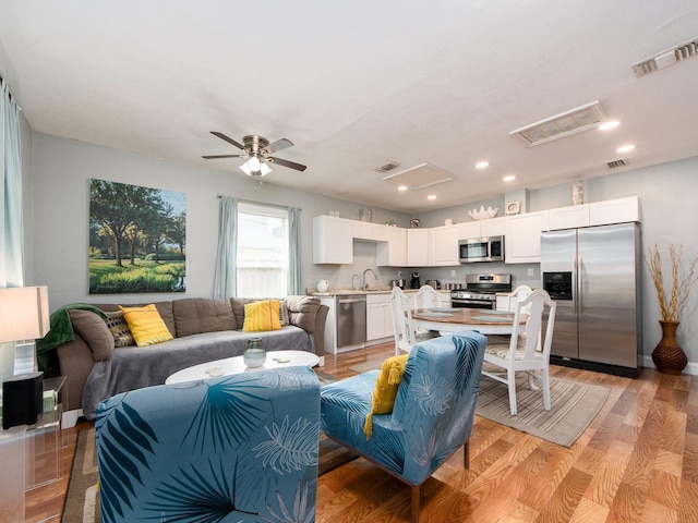 living room with light hardwood / wood-style floors, sink, and ceiling fan