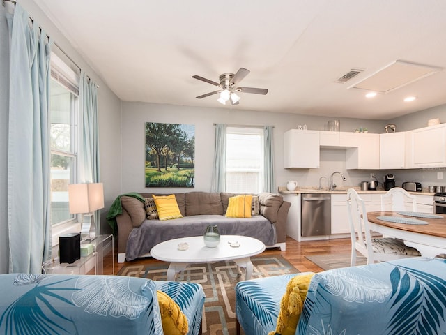 living room with ceiling fan, sink, and light hardwood / wood-style flooring