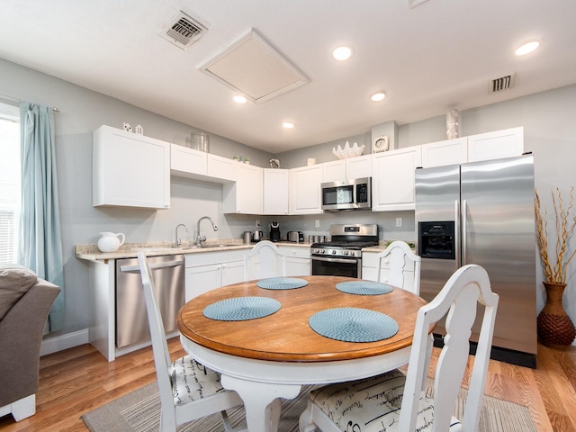 kitchen with sink, light wood-type flooring, white cabinetry, and stainless steel appliances