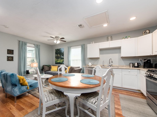 kitchen with light hardwood / wood-style flooring, white cabinets, ceiling fan, gas stove, and sink