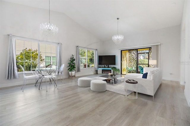 living room featuring a chandelier, high vaulted ceiling, and light wood-type flooring