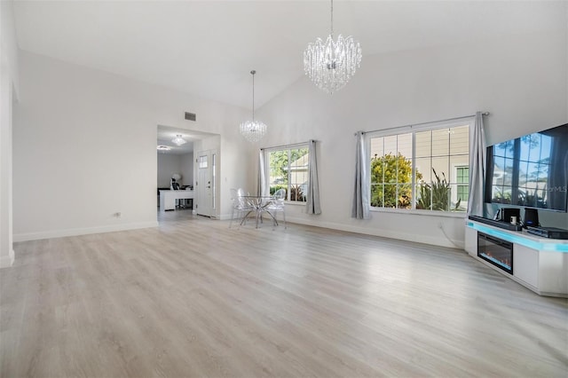 unfurnished living room with a chandelier, high vaulted ceiling, and light hardwood / wood-style flooring