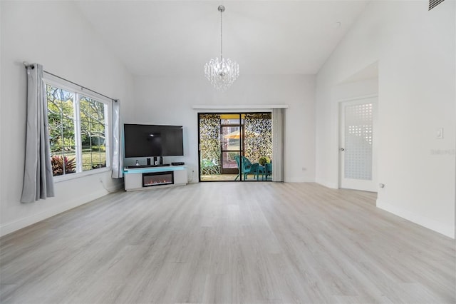 unfurnished living room with a notable chandelier, light hardwood / wood-style flooring, and high vaulted ceiling