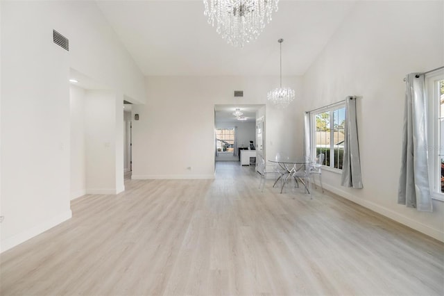 interior space with light wood-type flooring, high vaulted ceiling, and a notable chandelier