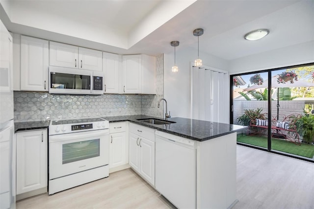 kitchen featuring sink, kitchen peninsula, pendant lighting, white appliances, and white cabinets