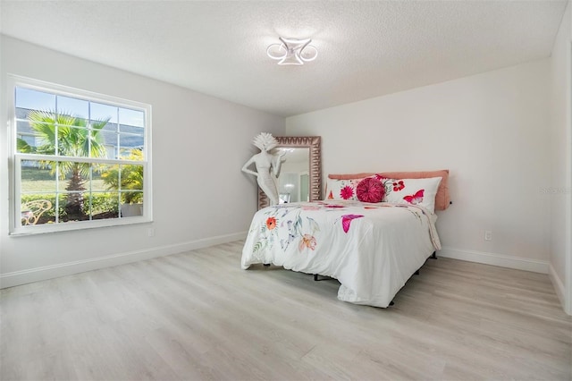 bedroom with a textured ceiling and light wood-type flooring