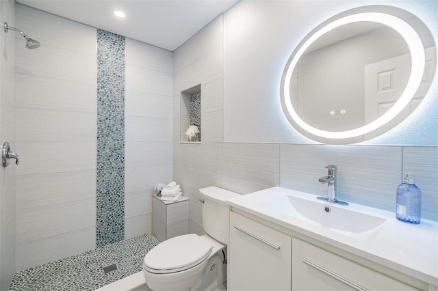 bathroom with vanity, toilet, tile walls, and a tile shower