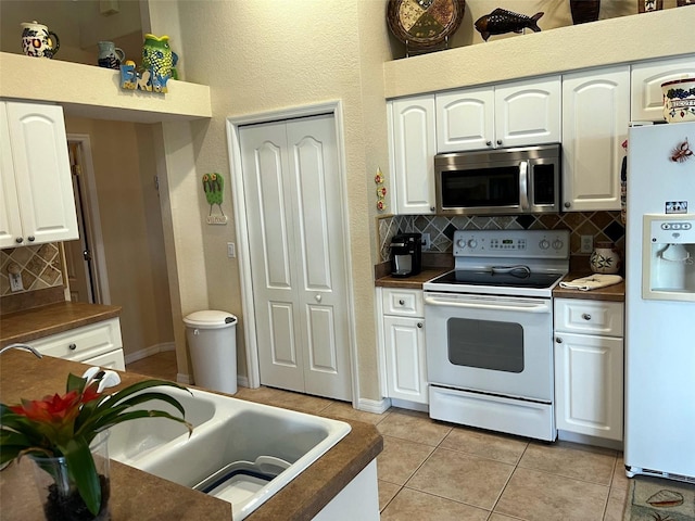 kitchen featuring white cabinetry, light tile patterned floors, and white appliances