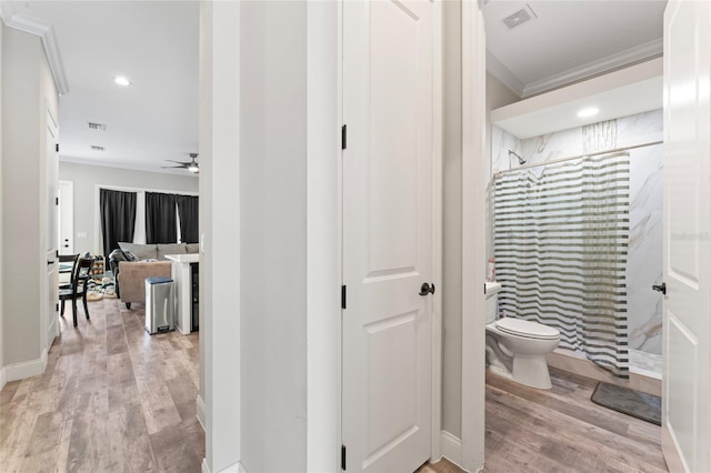 bathroom with a stall shower, visible vents, wood finished floors, and ornamental molding