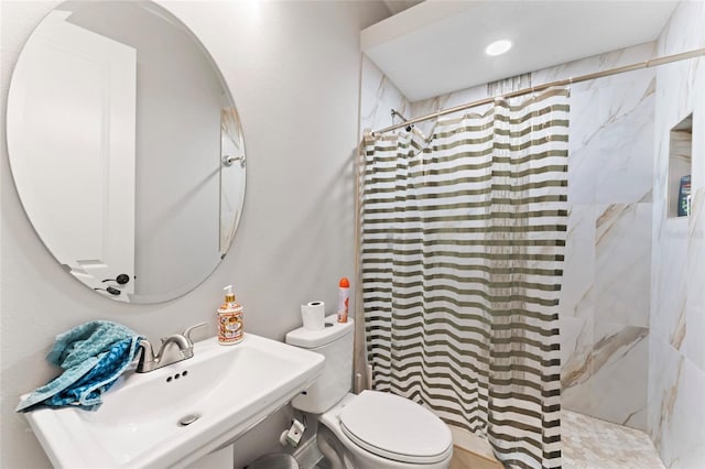 full bath featuring a sink, a tile shower, and toilet