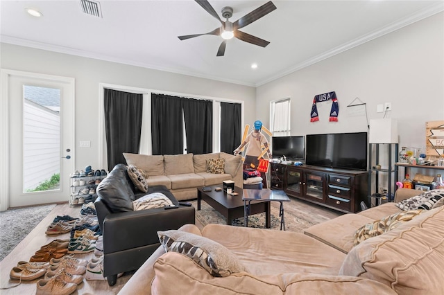 living area featuring light wood-type flooring, a ceiling fan, visible vents, and crown molding