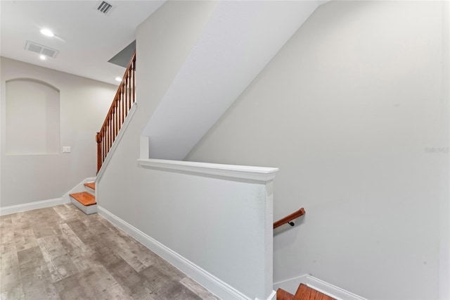 stairway with wood finished floors, visible vents, and baseboards