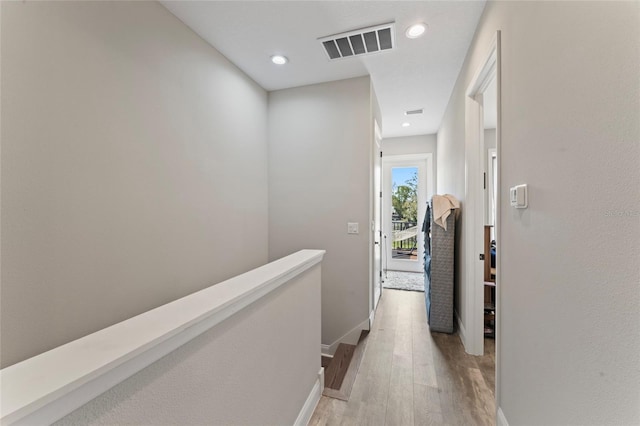 hall with recessed lighting, visible vents, an upstairs landing, light wood-type flooring, and baseboards