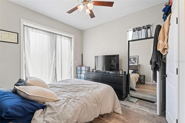 bedroom with ceiling fan, light wood-style flooring, and baseboards