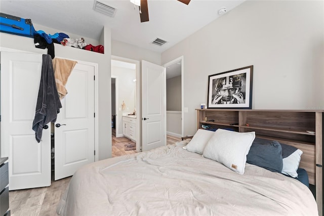 bedroom with light wood-type flooring, visible vents, ceiling fan, and ensuite bath