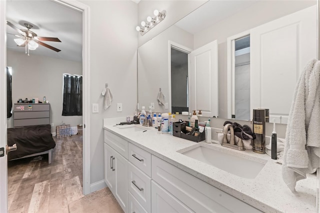 bathroom with wood finished floors, a sink, baseboards, and double vanity