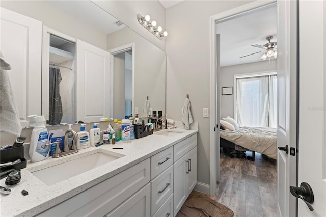 ensuite bathroom with ensuite bathroom, double vanity, wood finished floors, and a sink