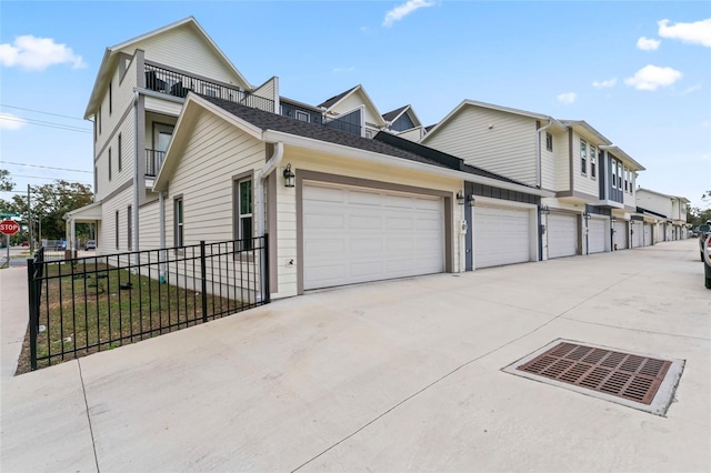 view of home's exterior featuring a garage, a shingled roof, fence, and concrete driveway